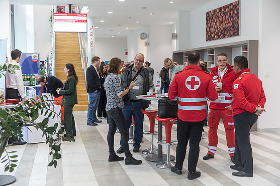 Foyer mit Menschen, die in Gruppen rund um Tische stehen