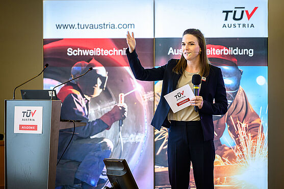 Pause gefällig? Bittesehr!<br /> Eine Frau mit blonen, langen Haaren und einem dunklen Business-Outfit hat den rechten Arm als Aufforderung erhoben.