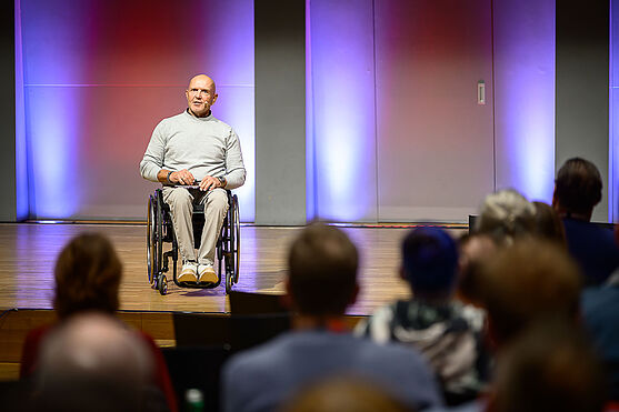 Der zweifache Paralympic-Sieger Walter Ablinger präsentierte seine inspirierende Keynote: Ich lasse mich nicht behindern.<br /> Mann im Rollstuhl hält Vortrag auf Bühne.
