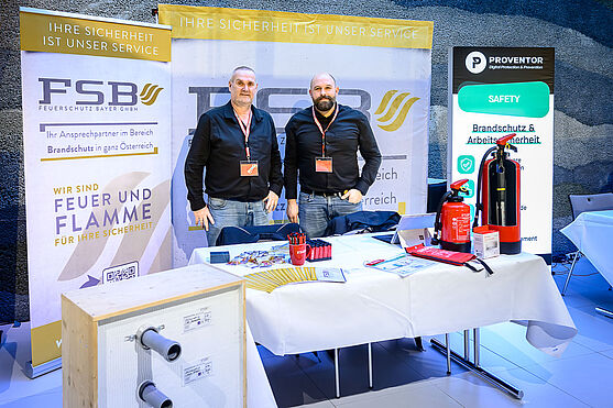 Zwei Männer hinter einem Ausstellerstand.