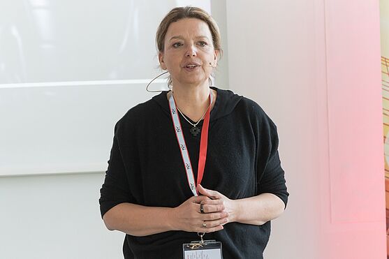 Dame mit Headset hält Vortrag vor einer Leinwand.