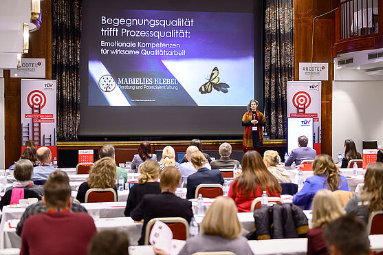 Dame auf der Bühne hält Vortrag.