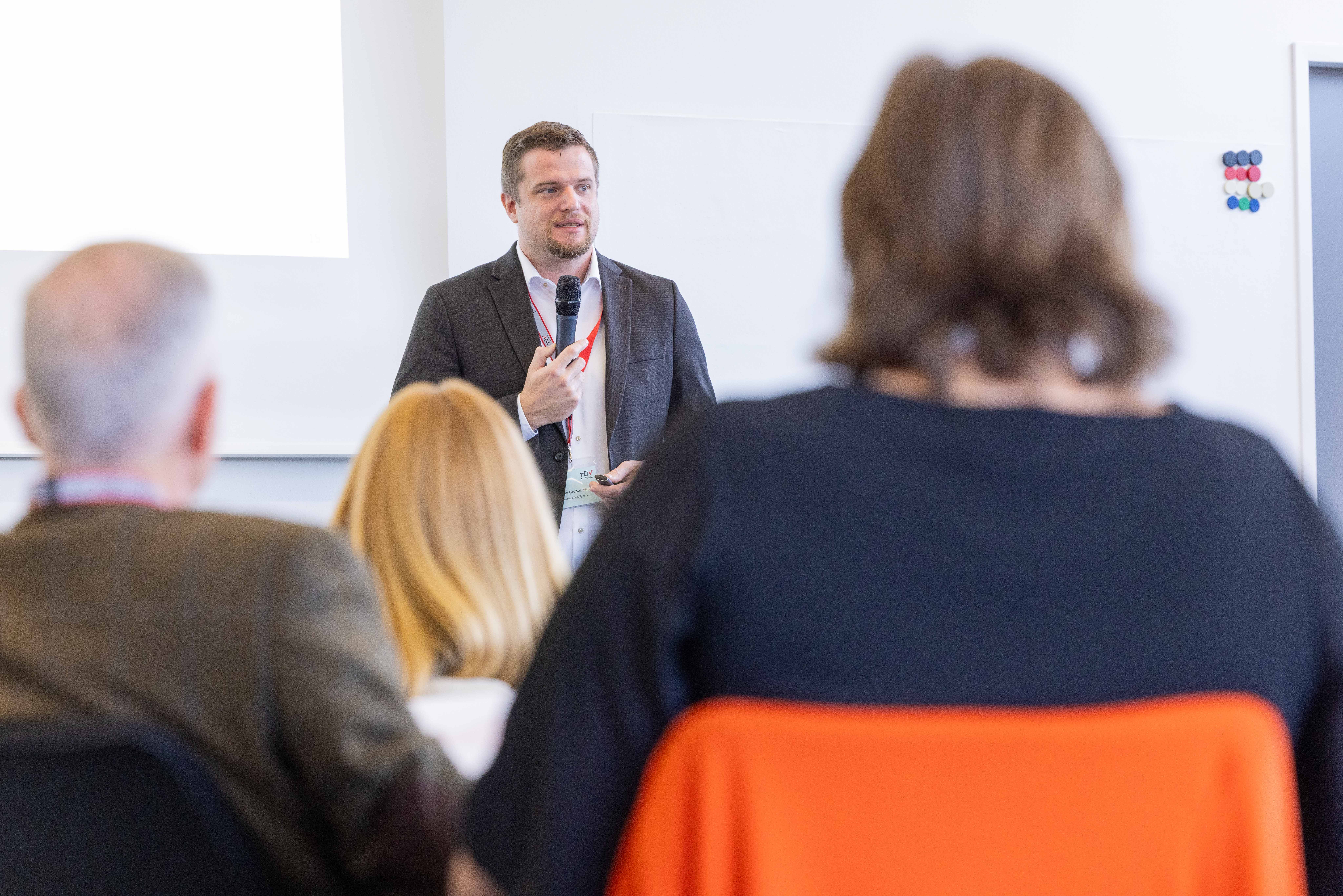 Andreas Gruber, MSc. MSc. (Technischer Berater für KI-Sicherheit) hielt den ersten Vortrag des Tages. KI für bessere Inklusion: Lösungen & Vorgaben.<br /> Mann hält Vortrag vor Publikum