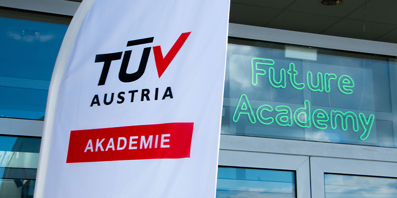 Ein Beachflag vor dem Eingang zur TÜV AUSTRIA Akademie in Gänserndorf. Dahinter eine Aufschrift auf der Tür: Future Academy.
